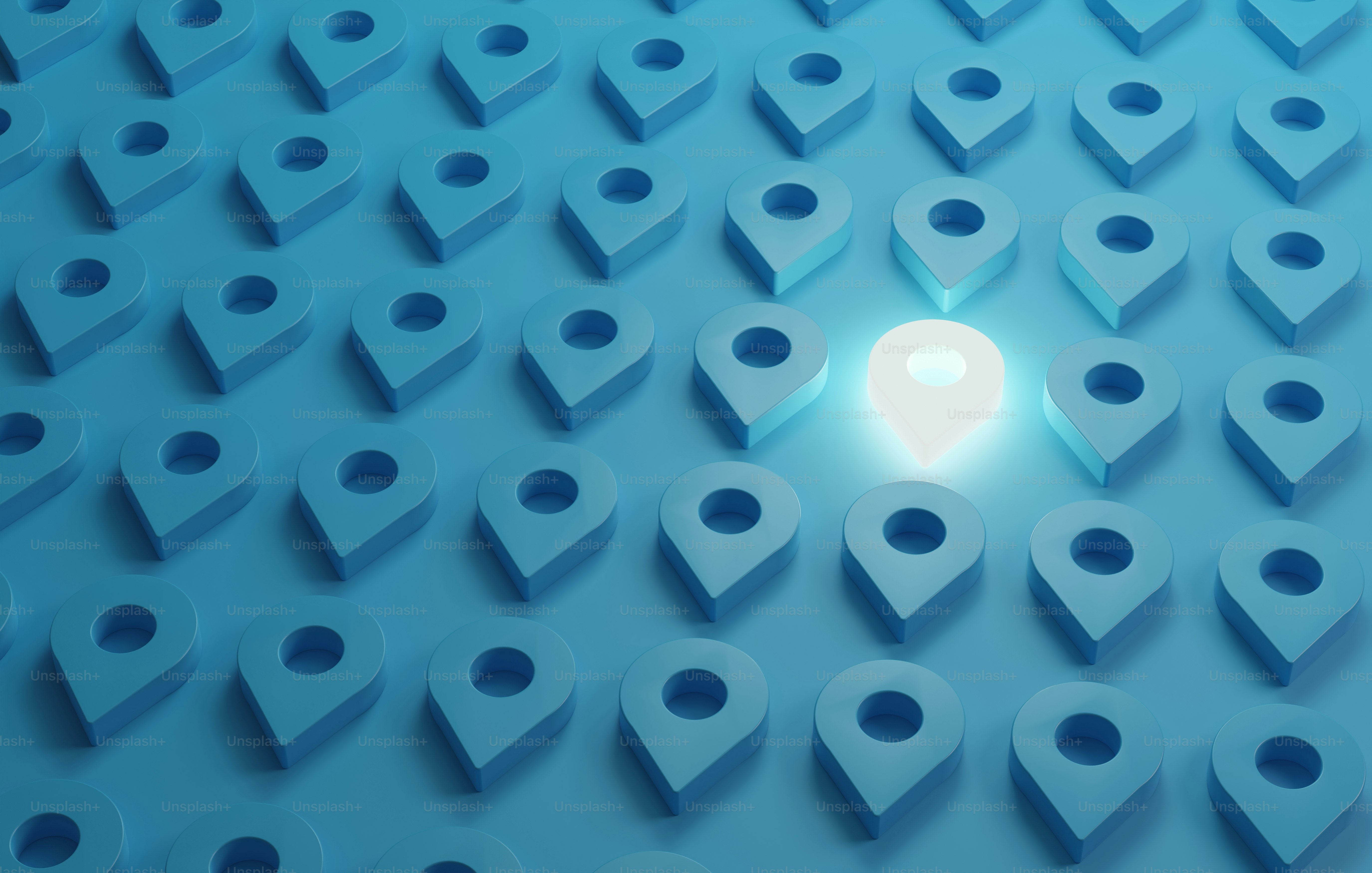 A glowing white location pin among many blue location pins on a surface